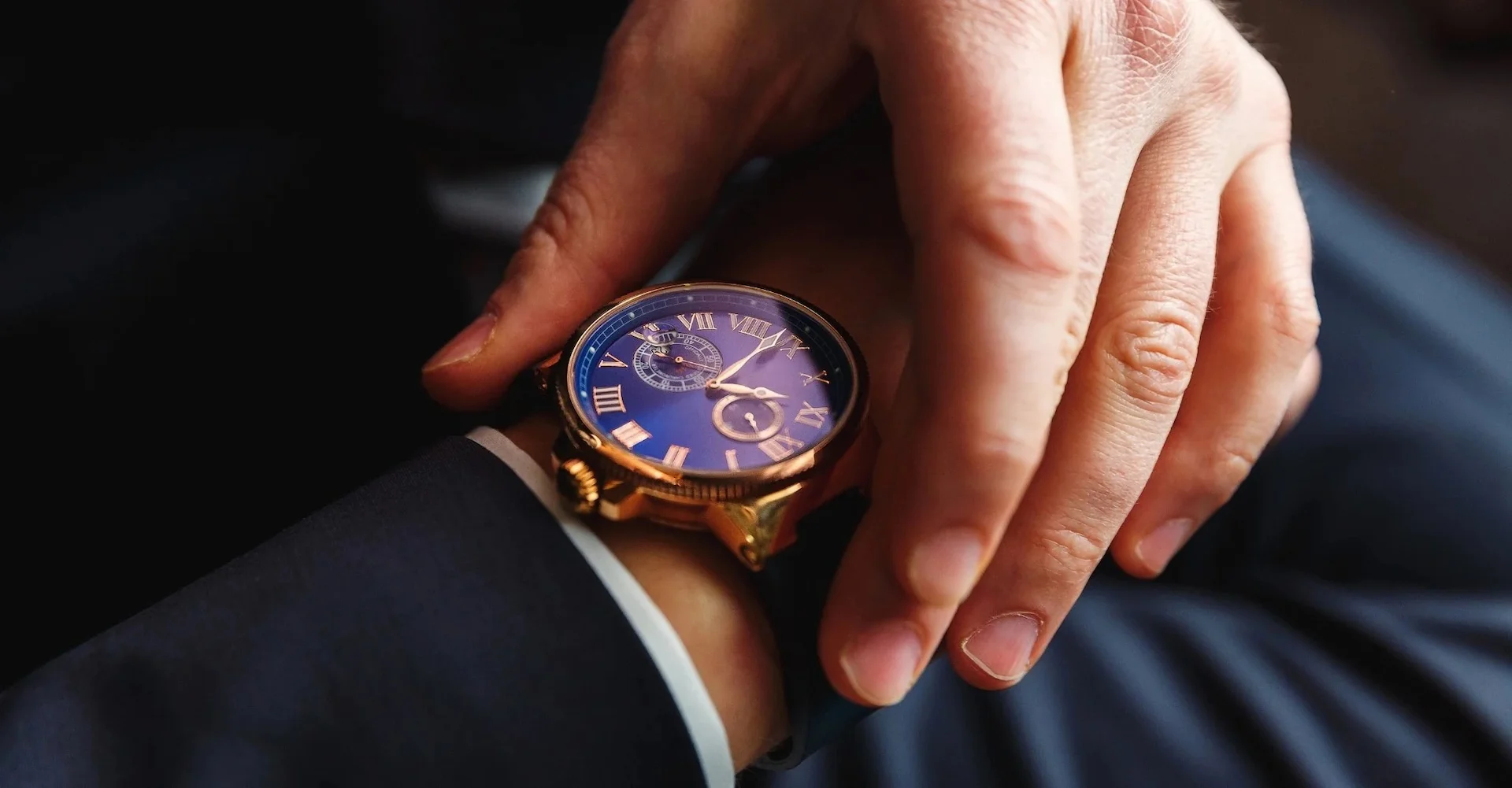 We see a closeup of a well-dressed man adjusting his expensive wristwatch.